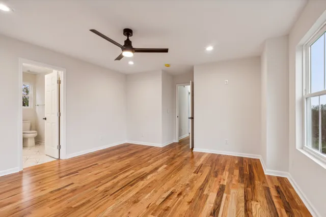 a view of empty room with wooden floor and fan