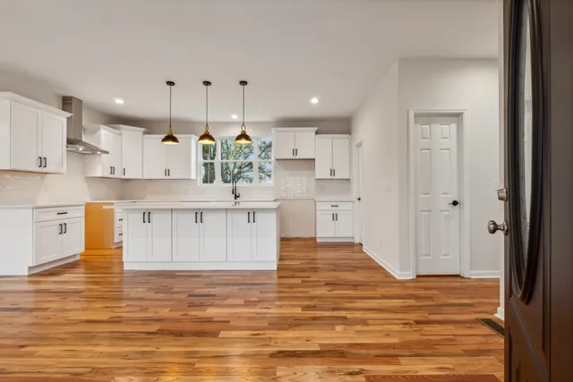 a large white kitchen with kitchen island a sink stainless steel appliances and cabinets