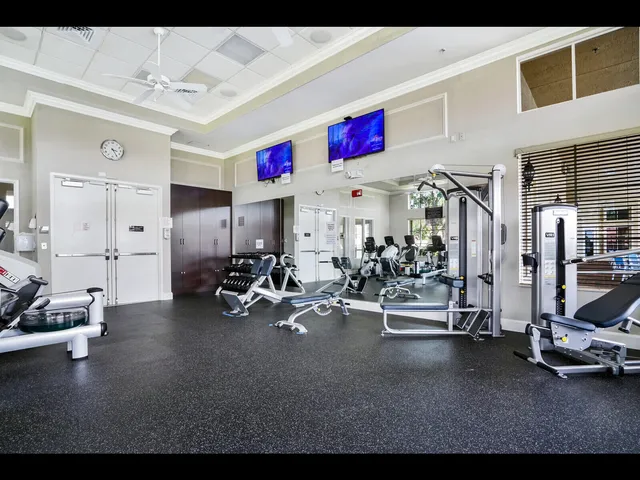 a living room with a gaming machine and a dining table with wooden floor