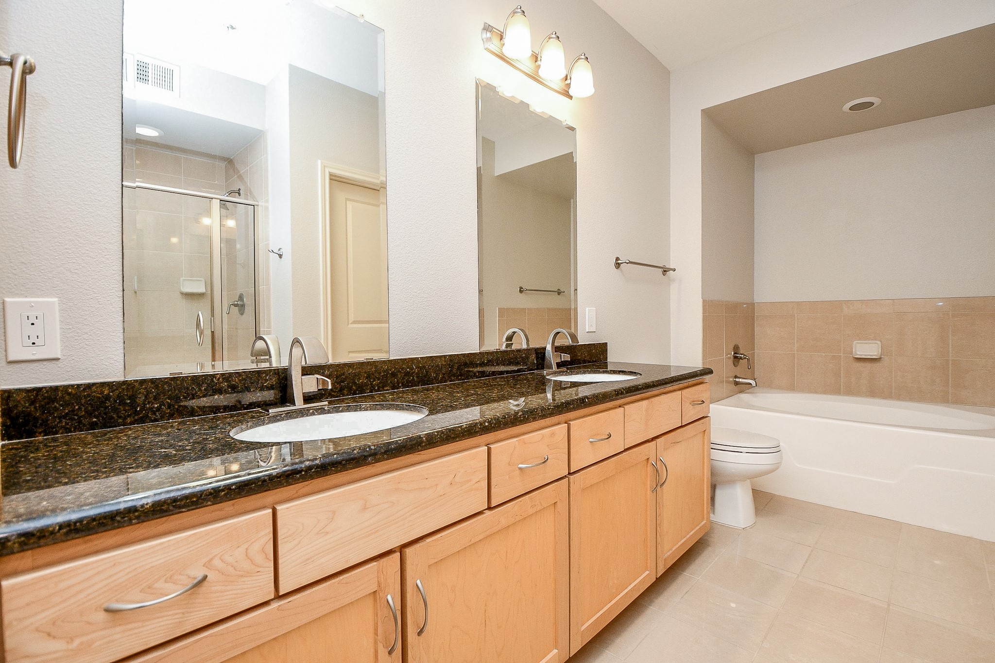 505 Jackson Hill Street, Unit 307 Houston, TX 77007 - Photo 12 of 30 a bathroom with a granite countertop double vanity sink a mirror and a bathtub