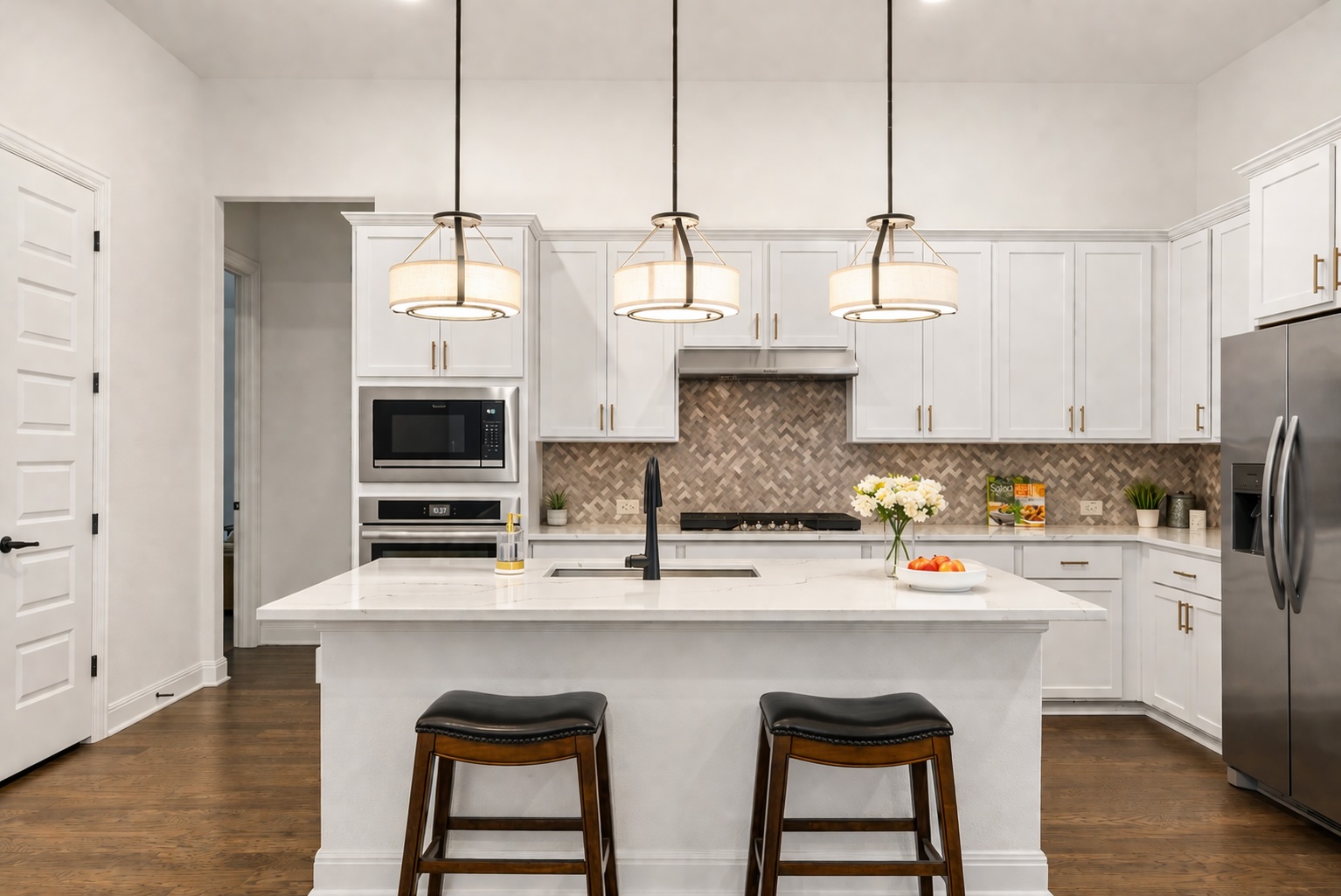 209 Rainier Drive Kyle, TX 78640 - Photo 3 of 24 Kitchen featuring a central island with a sink and pendant lighting, white cabinetry, integrated stainless steel appliances, and wood-finish flooring