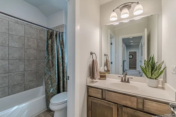 a bathroom with a sink a toilet a mirror a bathtub and shower