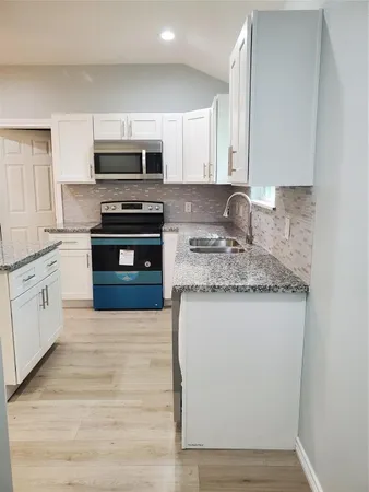 a kitchen with stainless steel appliances granite countertop a stove a sink and a microwave
