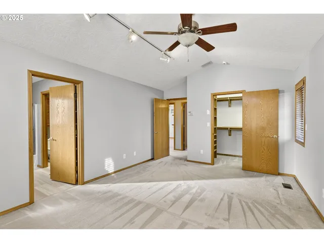 a view of an empty room with window and a ceiling fan