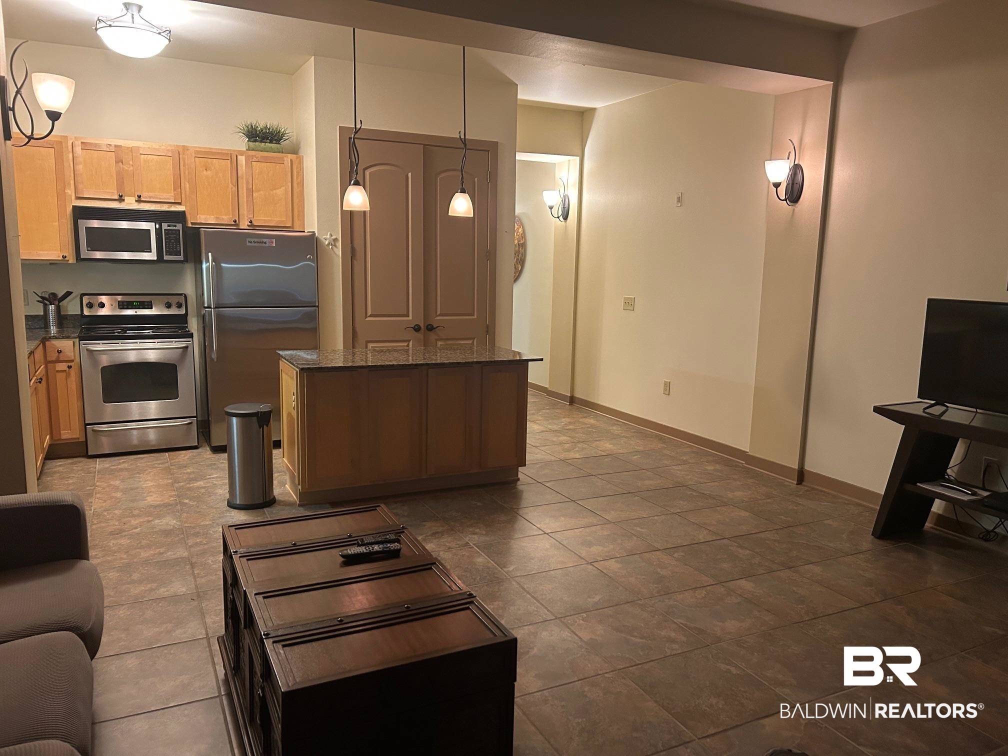 1430 Regency Road, Unit J102 Gulf Shores, AL 36542 - Photo 5 of 11 Kitchen with pendant lighting, a kitchen island, light brown cabinets, stainless steel appliances, and dark stone countertops