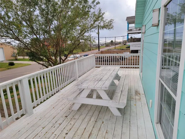 a balcony with wooden floor outdoor seating and yard in the back