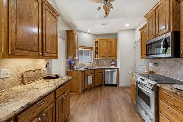 a kitchen with granite countertop stainless steel appliances a sink stove top oven and cabinets