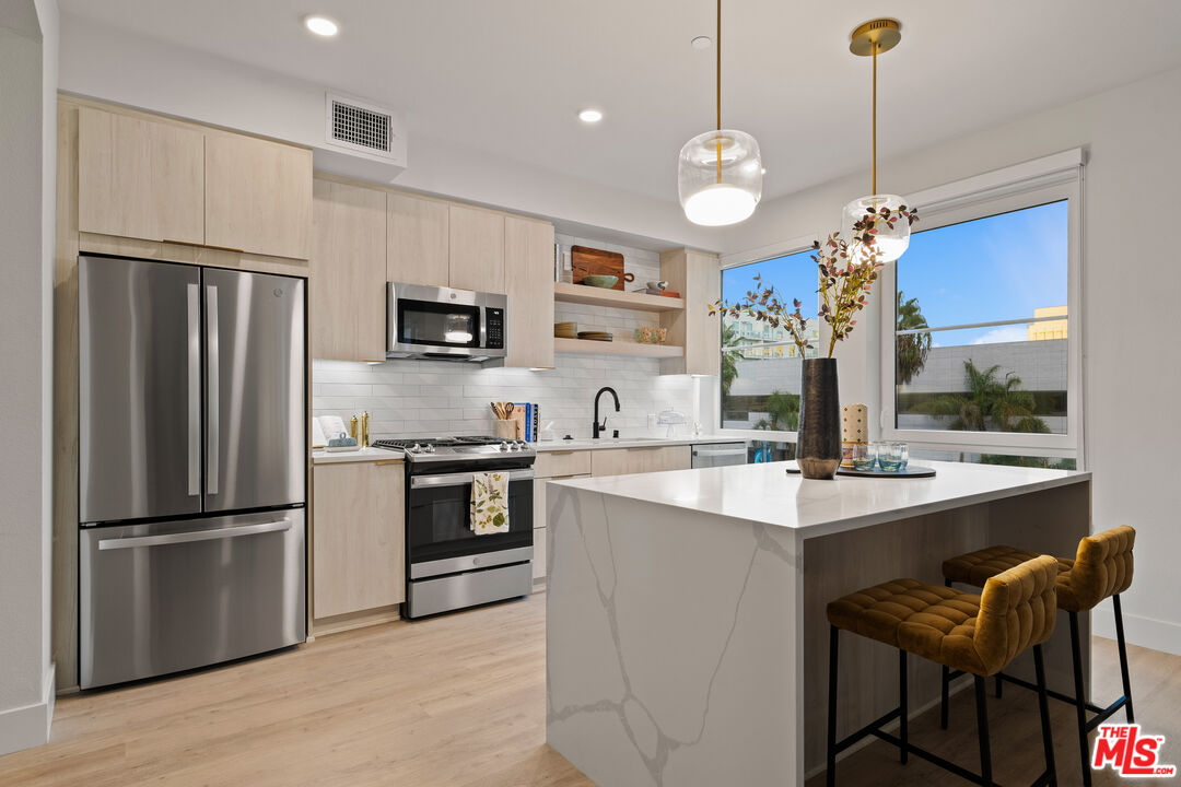 250 East Broadway, Unit 803 Long Beach, CA 90802 - Photo 31 of 44 a kitchen with stainless steel appliances granite countertop a stove a refrigerator a sink a oven a dining table and chairs with wooden floor