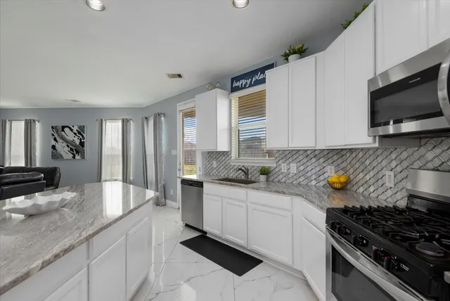 a kitchen with stainless steel appliances a stove a sink and a microwave