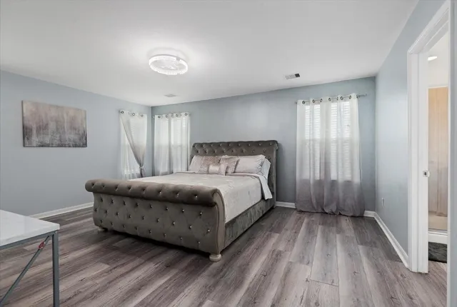 a spacious bedroom with a bed and wooden floor