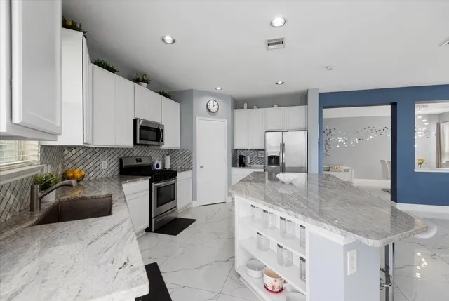 a kitchen with stainless steel appliances granite countertop a sink a stove top oven a counter space and cabinets