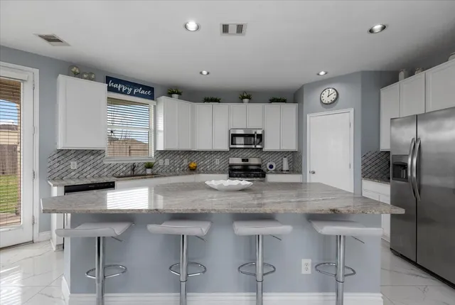 a kitchen with stainless steel appliances granite countertop a stove a sink a microwave a refrigerator and cabinets