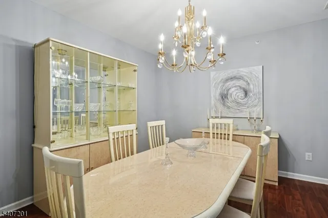a dining room with wooden floor a chandelier a wooden table and chairs