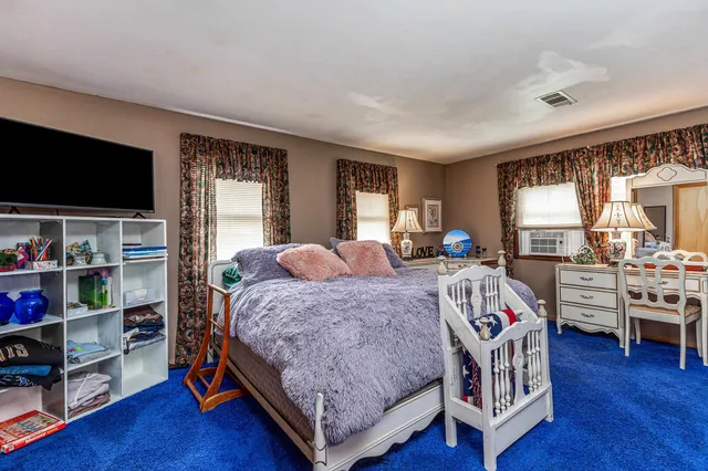 a bedroom with a large bed and a flat tv screen on dresser