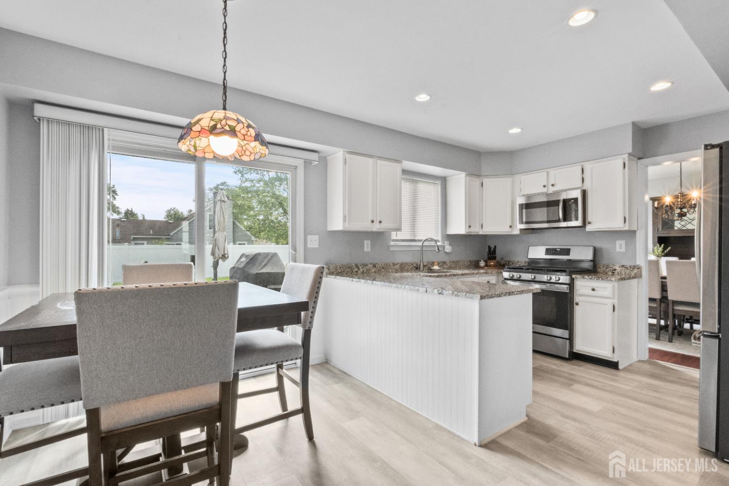3 Mendon Drive Howell, NJ 07731 - Photo 9 of 23 a kitchen with stainless steel appliances granite countertop a stove top oven a refrigerator a sink and a dining table with wooden floor