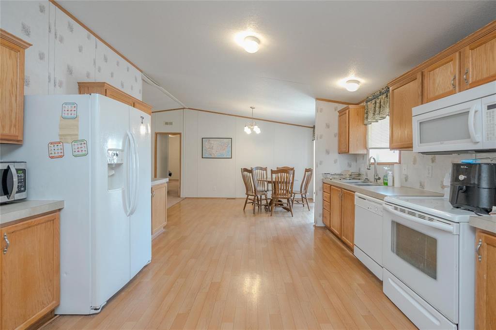 4260 Couch Road Ponder, TX 76259 - Photo 17 of 25 a kitchen with stainless steel appliances granite countertop a stove a sink a refrigerator and white cabinets with wooden floor