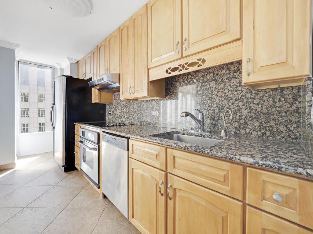 100 East Walton Street, Unit 27B Chicago, IL 60611 - Photo 7 of 18 a kitchen with granite countertop white cabinets and stainless steel appliances