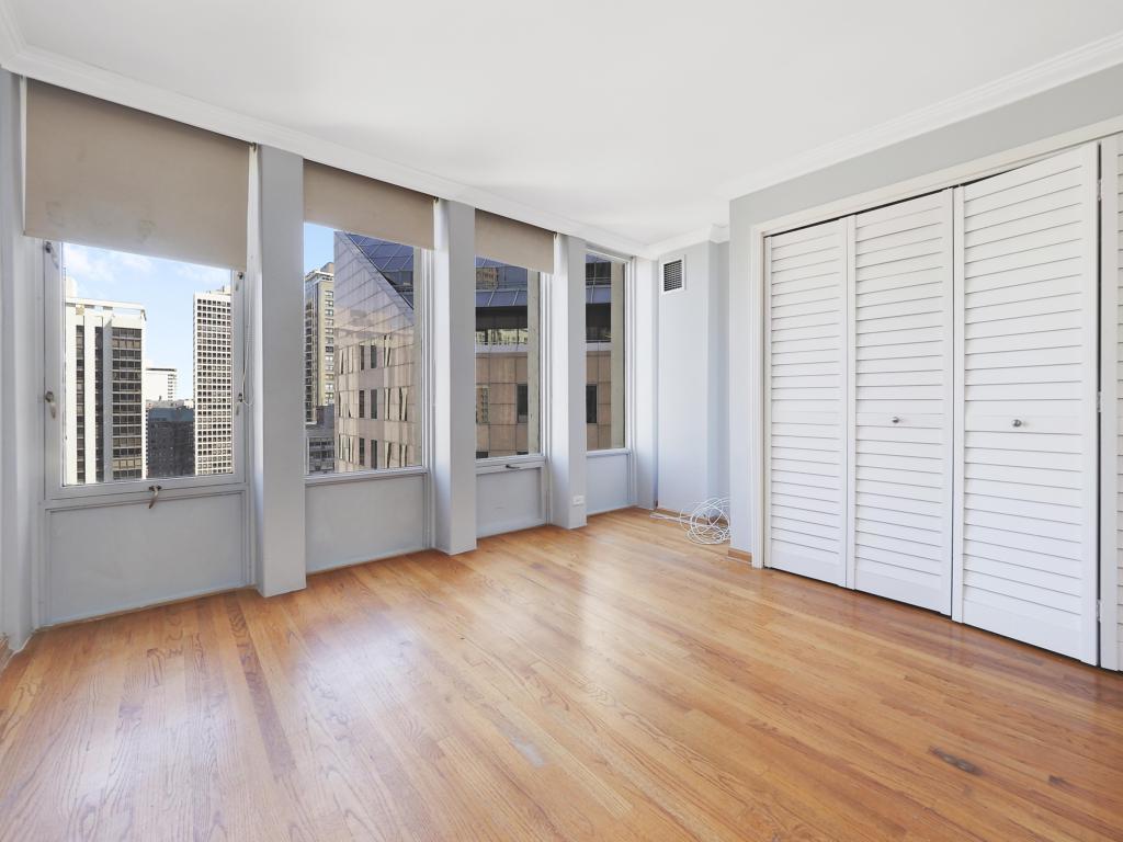100 East Walton Street, Unit 27B Chicago, IL 60611 - Photo 10 of 18 an empty room with wooden floor and windows