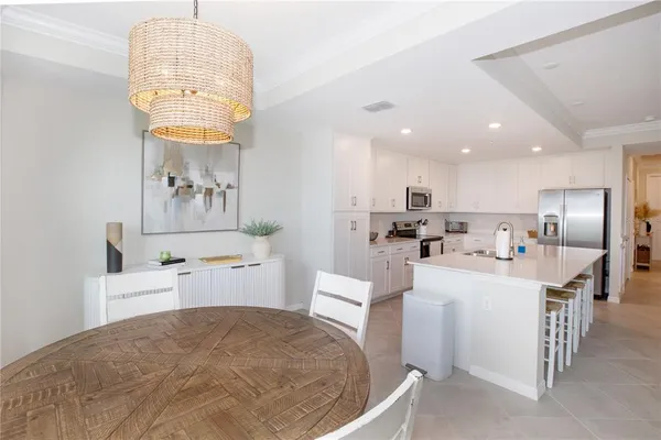 a large white kitchen with a white countertops a stove a dining table and chairs