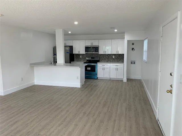 a view of kitchen with stainless steel appliances kitchen island wooden floors and granite counter tops