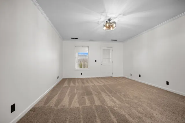 a view of an empty room with a chandelier fan