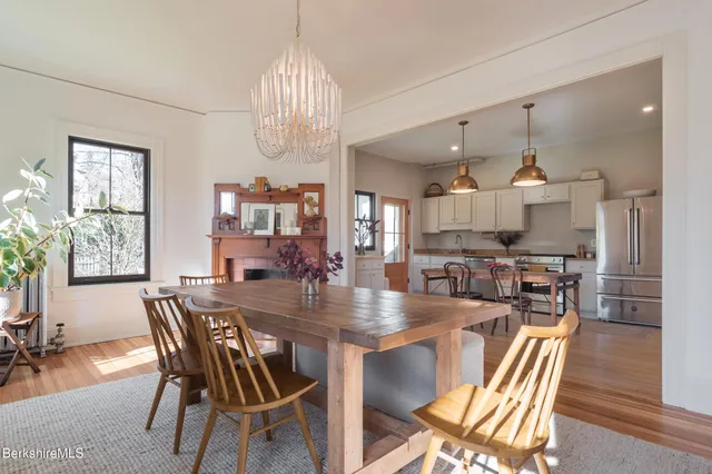 a kitchen with stainless steel appliances granite countertop a refrigerator a sink dishwasher a stove and white cabinets with wooden floor