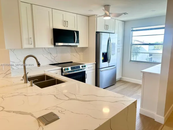 a kitchen with stainless steel appliances a refrigerator a sink a stove and microwave