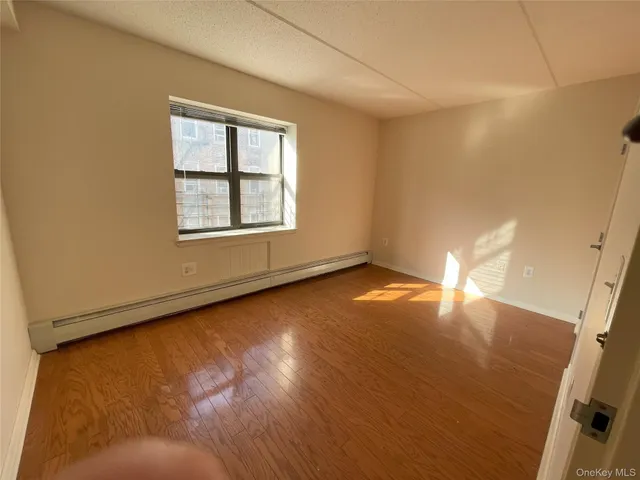 an empty room with wooden floor and windows with curtains