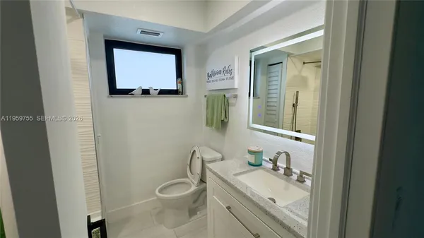 a bathroom with a toilet sink vanity granite and mirror