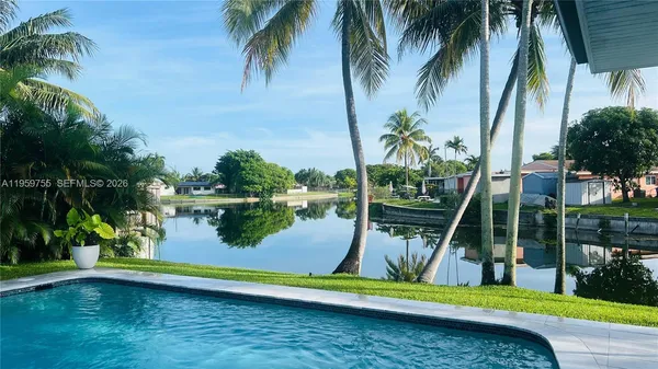 a view of swimming pool with a lake and palm trees