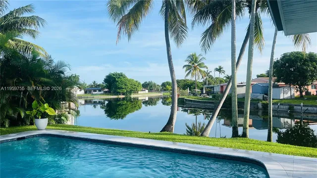 a view of swimming pool with a lake and palm trees