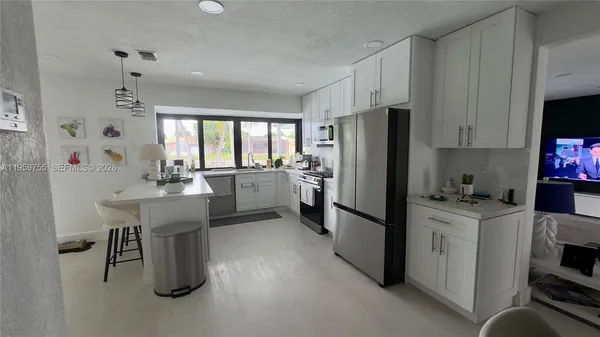 a kitchen with a refrigerator a sink dishwasher and a stove with wooden floor