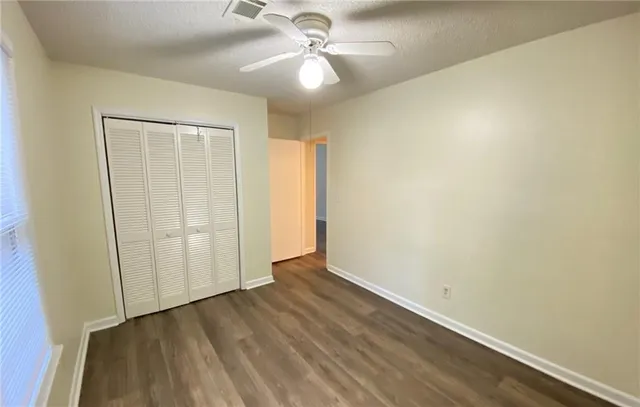 a view of empty room with wooden floor and fan