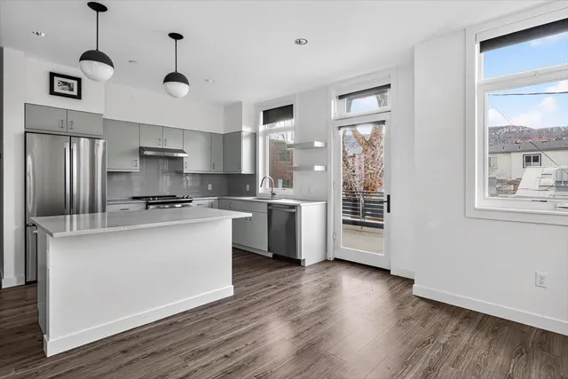 a kitchen with stainless steel appliances granite countertop a refrigerator a stove a sink dishwasher a oven with white cabinets and wooden floor