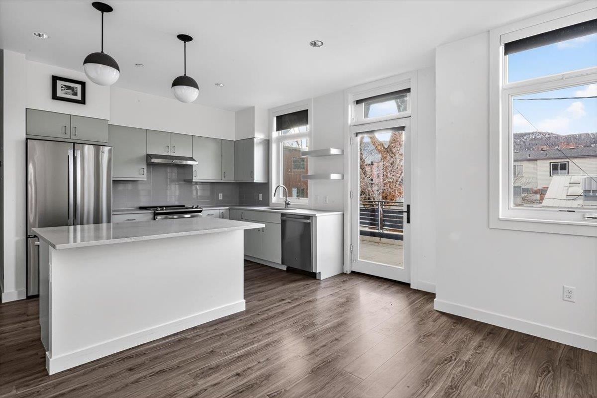 185 North Lena Street, Unit CONDO D Ridgway, CO 81432 - Photo 5 of 17 a kitchen with stainless steel appliances granite countertop a refrigerator a stove a sink dishwasher a oven with white cabinets and wooden floor