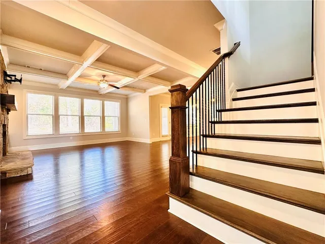 a view of an empty room with wooden floor and a fireplace