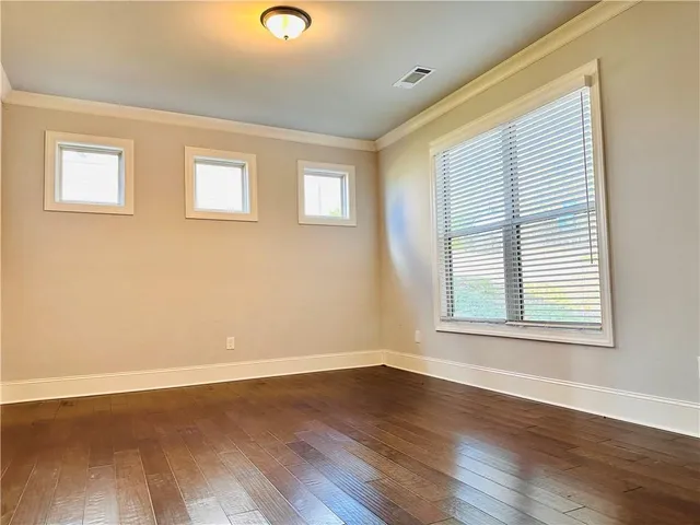 an empty room with wooden floor fireplace and windows