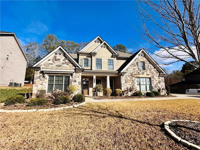 a view of a livingroom with wooden floor a ceiling fan and windows