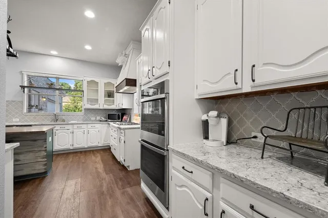 a kitchen with granite countertop white cabinets and white appliances