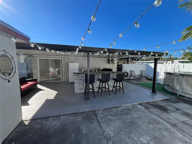 a view of a patio with table and chairs with plants and barbeque grill