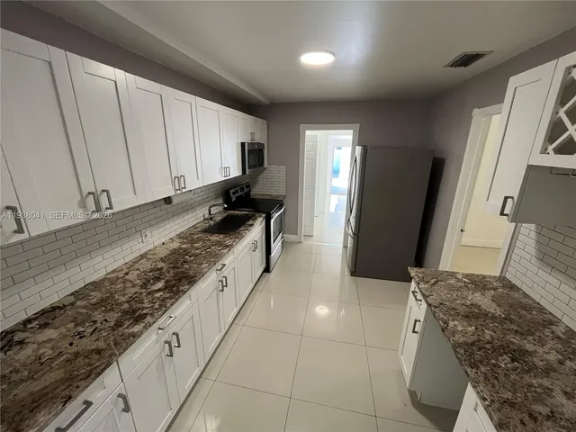a large kitchen with kitchen island granite countertop a sink a stove a washer and dryer