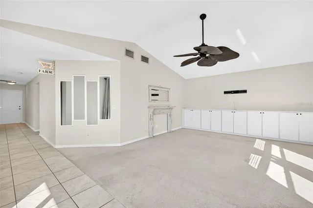 a view of an empty room and chandelier fan