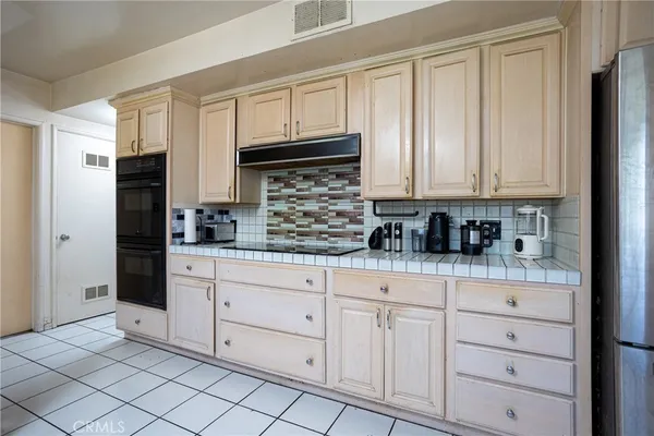 a kitchen with white cabinets and refrigerator