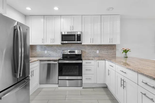 a kitchen with granite countertop a refrigerator sink and cabinets