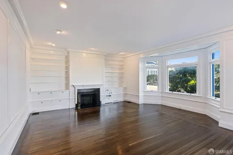 a view of empty room with wooden floor and fireplace
