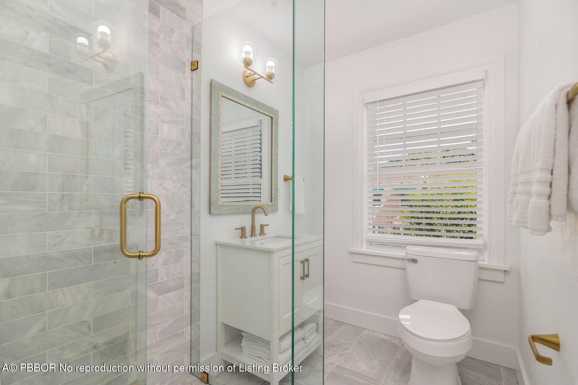 3020 Vincent Road West Palm Beach, FL 33405 - Photo 19 of 56 a bathroom with a granite countertop toilet a sink a shower and mirror