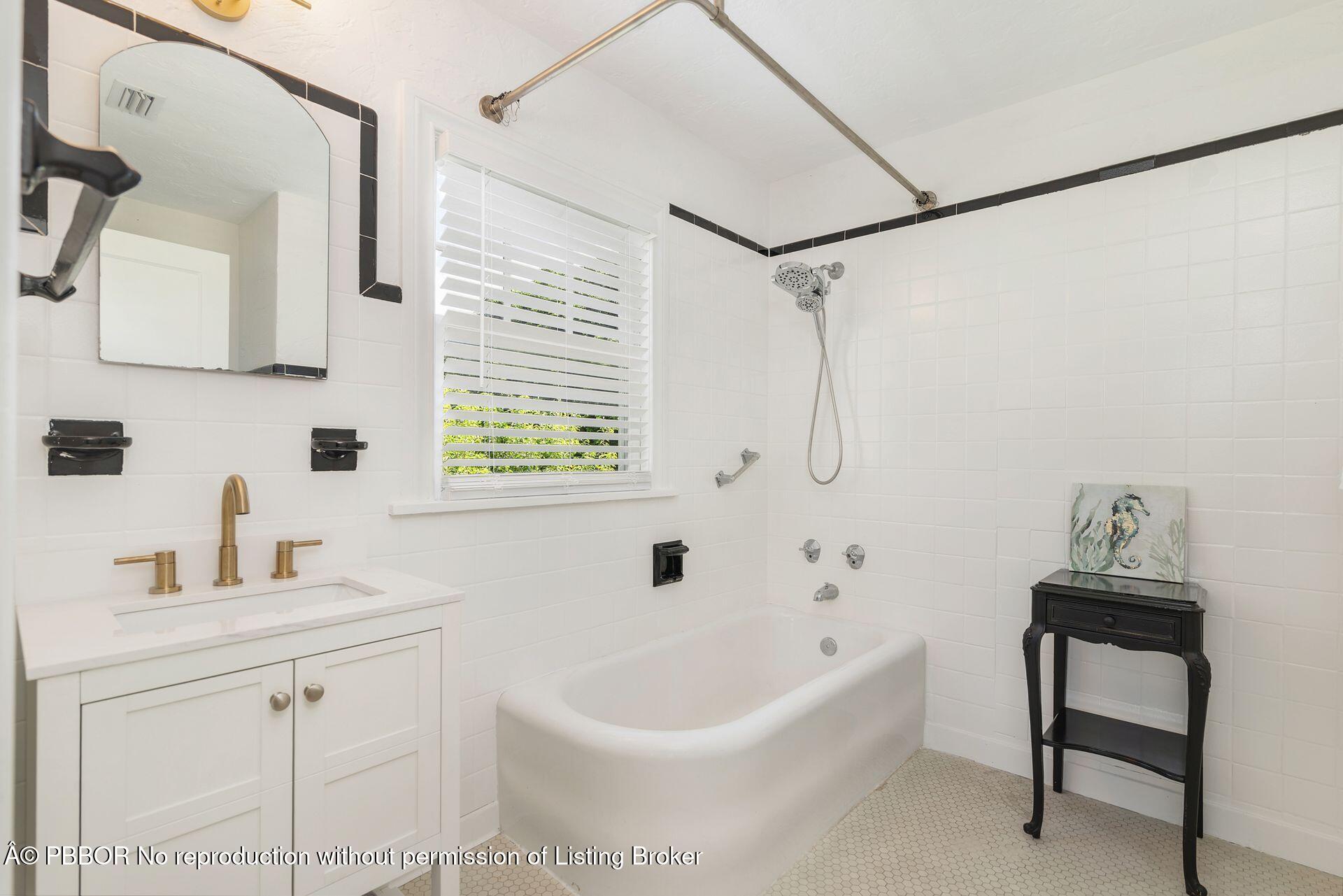 3020 Vincent Road West Palm Beach, FL 33405 - Photo 21 of 56 a white bath tub sitting next to a white sink and a mirror