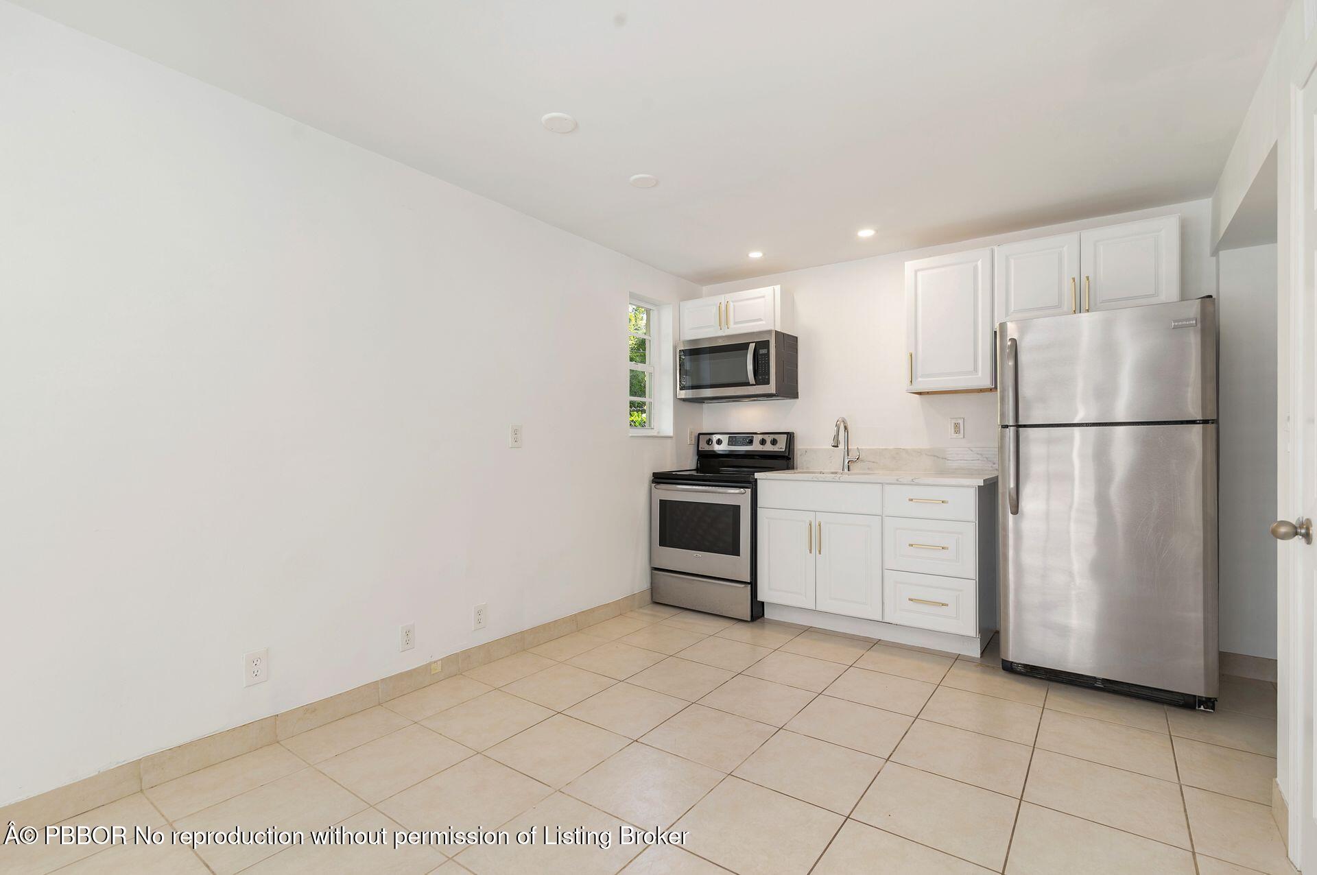 3020 Vincent Road West Palm Beach, FL 33405 - Photo 25 of 56 a kitchen with a refrigerator a stove top oven and white cabinets