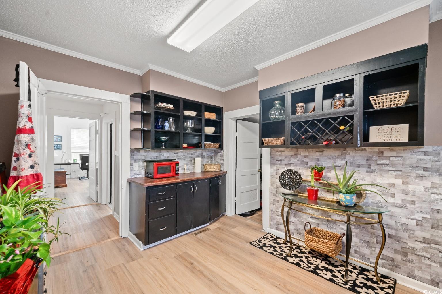 222 East Wine Street Mullins, SC 29574 - Photo 12 of 40 Indoor dry bar with crown molding, dark cabinets, open shelves, a textured ceiling, and light wood-type flooring