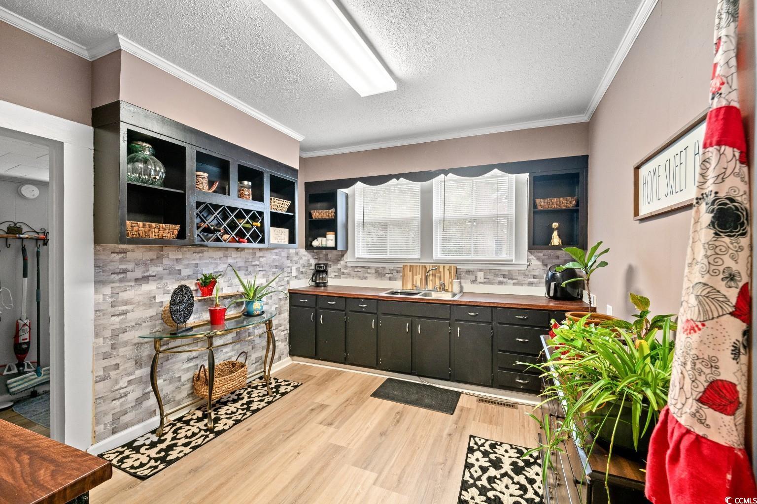 222 East Wine Street Mullins, SC 29574 - Photo 17 of 40 Kitchen with open shelves, a textured ceiling, light wood-type flooring, ornamental molding, and wooden counters